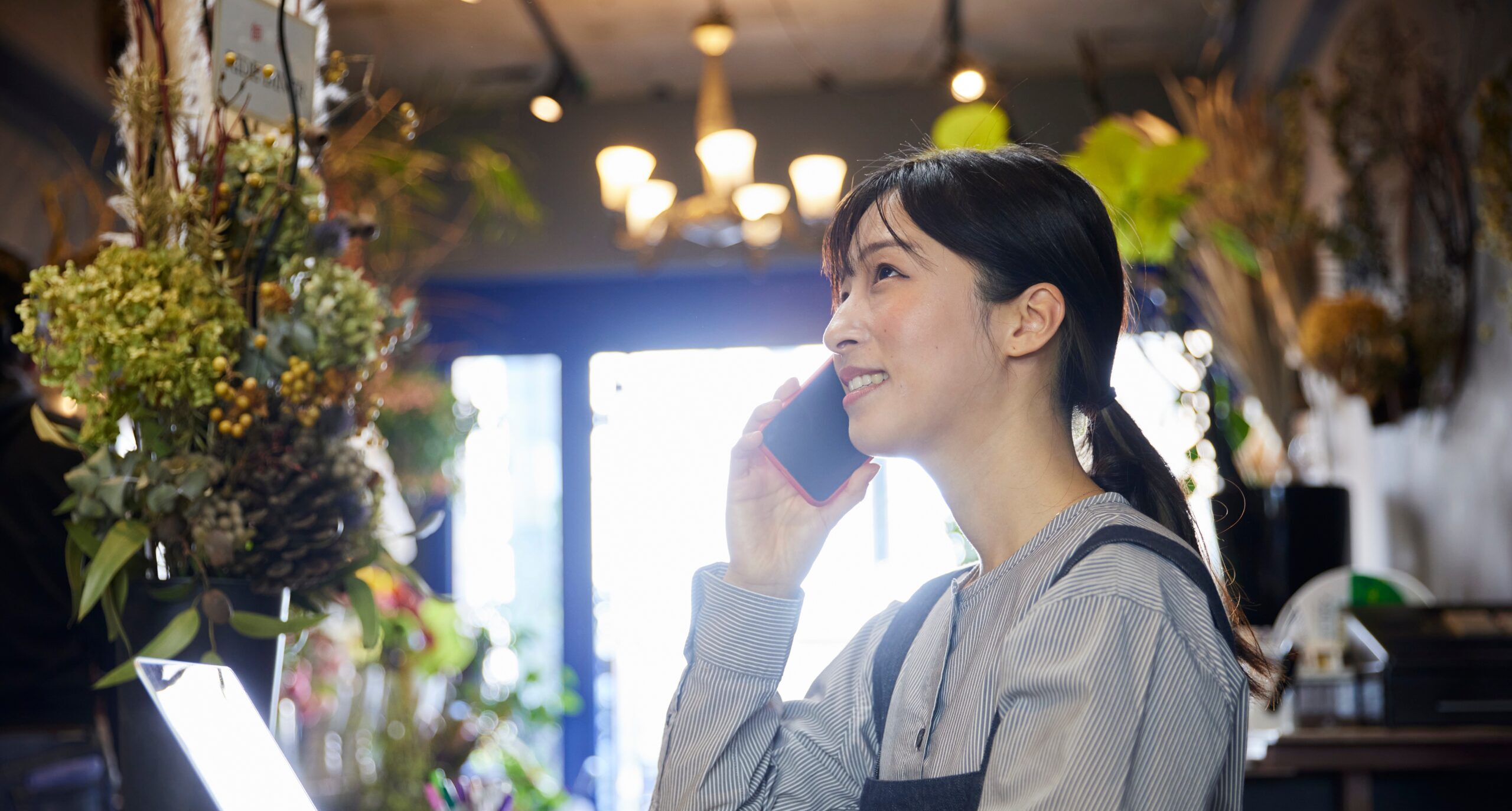 Japanese,Woman,Working,At,A,Flower,Shop,Using,A,Smartphone