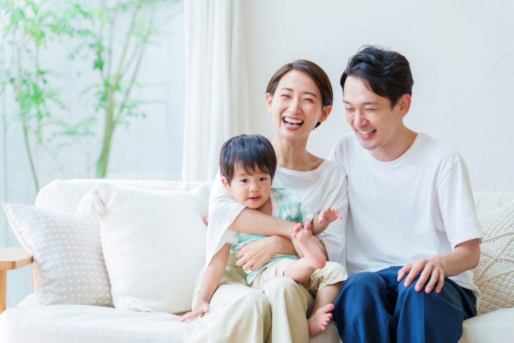 幼い子どもとソファでくつろぐ若い夫婦